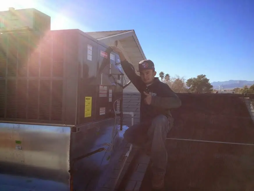 HVAC technician performing Air Duct Cleaning on a rooftop unit in Freeport